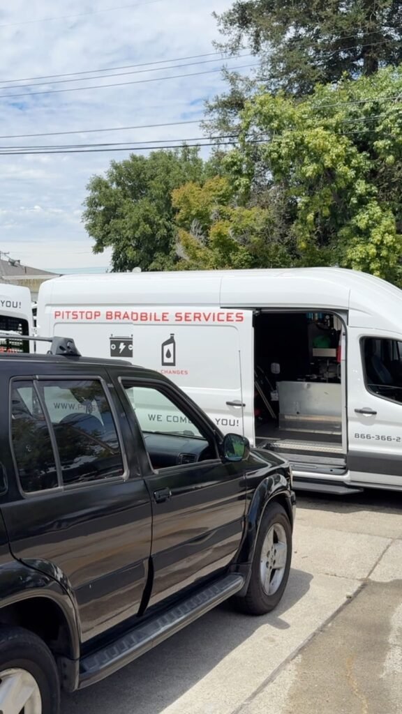PitStop mobile mechanic van with the side door open showing service equipment, parked beside a black Infiniti QX4 for a check engine light diagnostic in Concord California